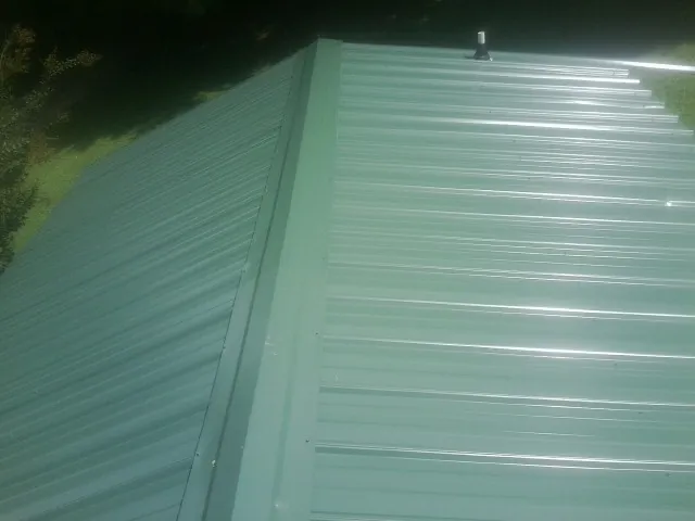 New green metal panels meeting at the ridge of a roof — Flat Roof Repair work by our crew in Manti