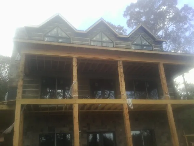 Dormers and porch framing on a large log home under construction — Roof Coating work by our crew in Manti