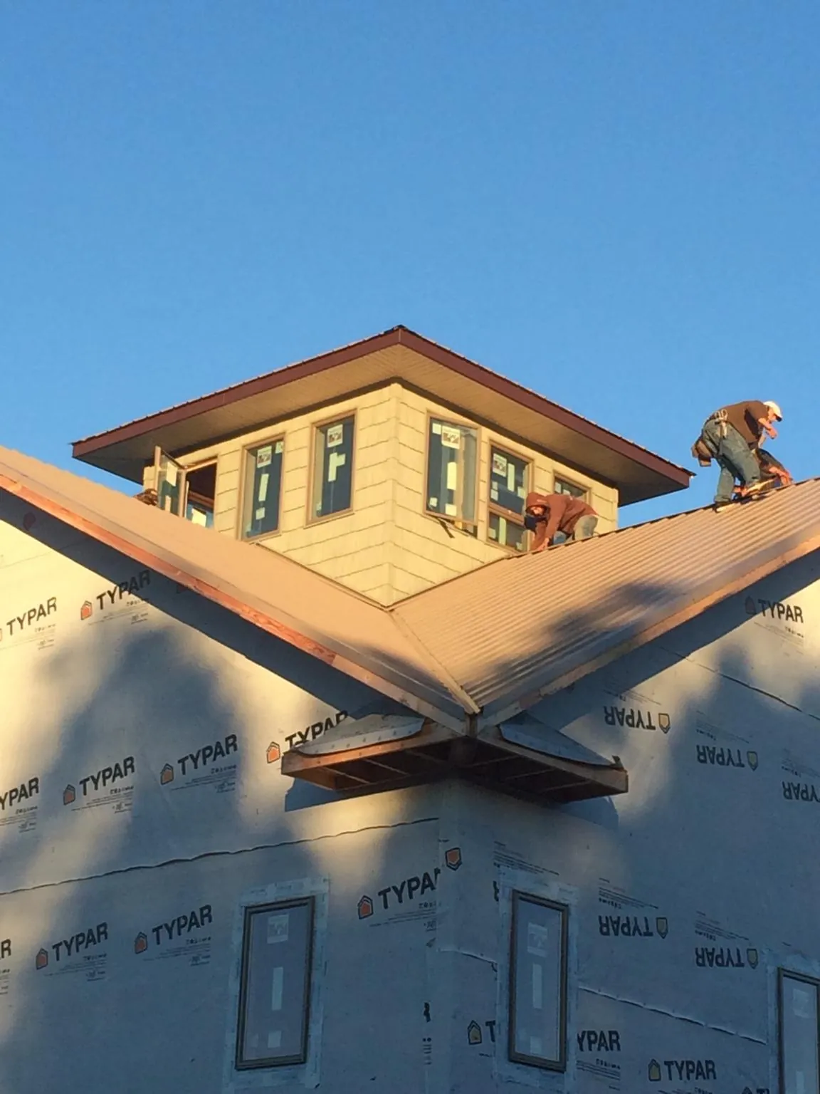 Roofers working around a rooftop cupola on a new metal roof at sunset — Roof Waterproofing in Manti by Roofing Brothers